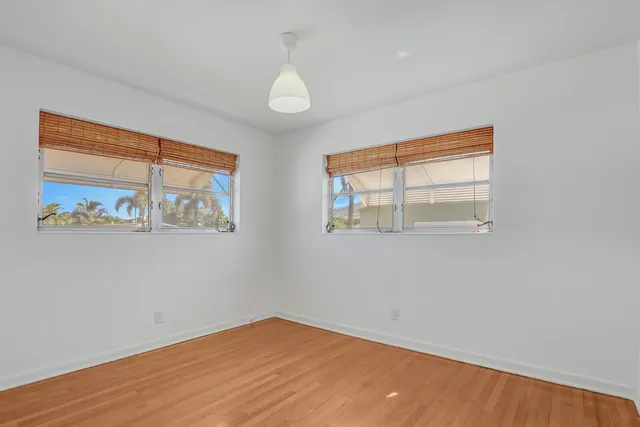 an empty room with wooden floor and window