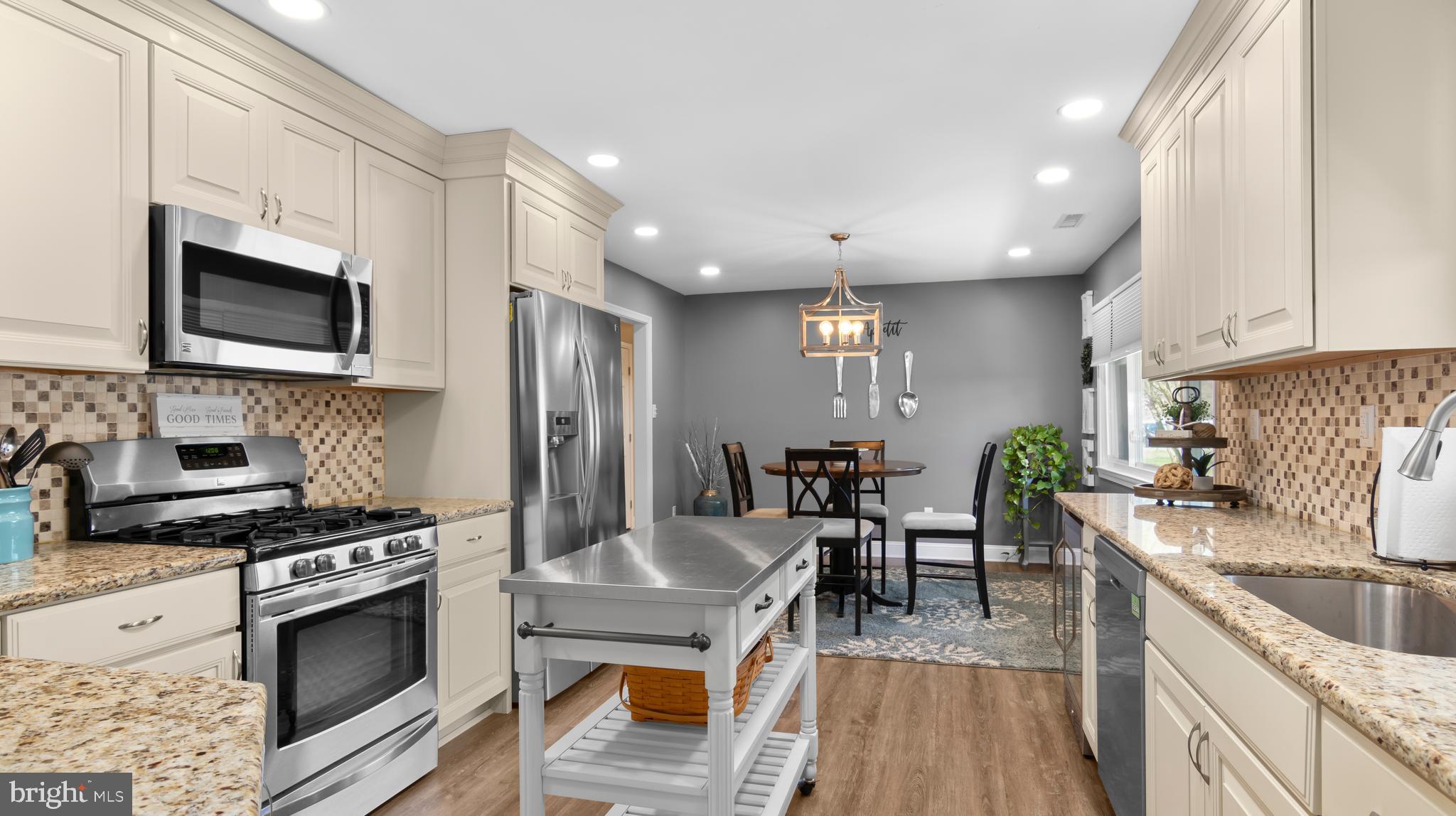 5505 Whitehall Road Cambridge, MD 21613 - Photo 10 of 44 a kitchen with stainless steel appliances granite countertop a stove top oven a sink dishwasher a dining table and chairs with wooden floor