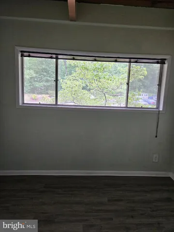 a view of empty room with wooden floor and a window