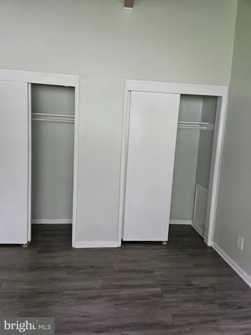 a view of an empty room with wooden floor and closet