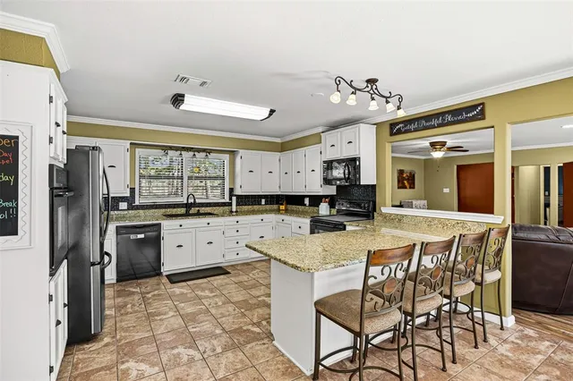 a kitchen with granite countertop a sink a stove and cabinets