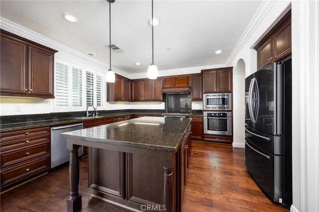 a kitchen with stainless steel appliances granite countertop a sink a stove and a refrigerator