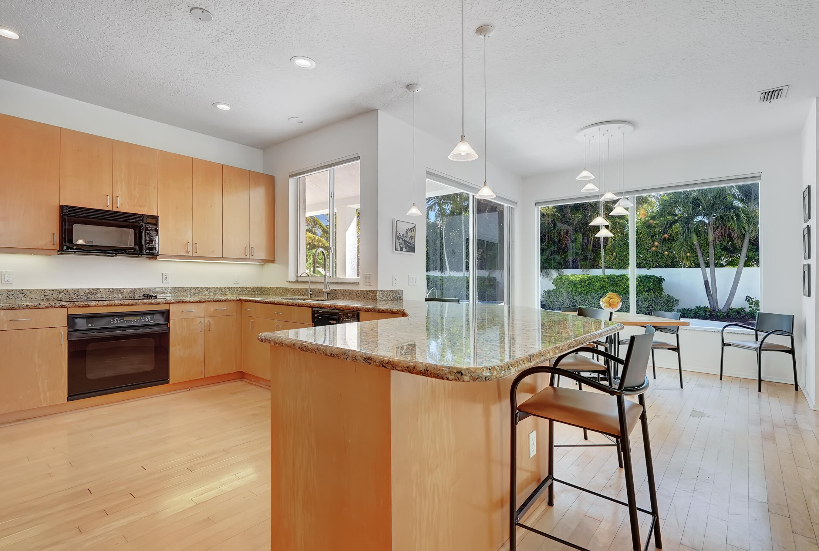 114 Olympus Circle Jupiter, FL 33477 - Photo 29 of 88 a kitchen with stainless steel appliances granite countertop wooden cabinets a stove a sink and a large window