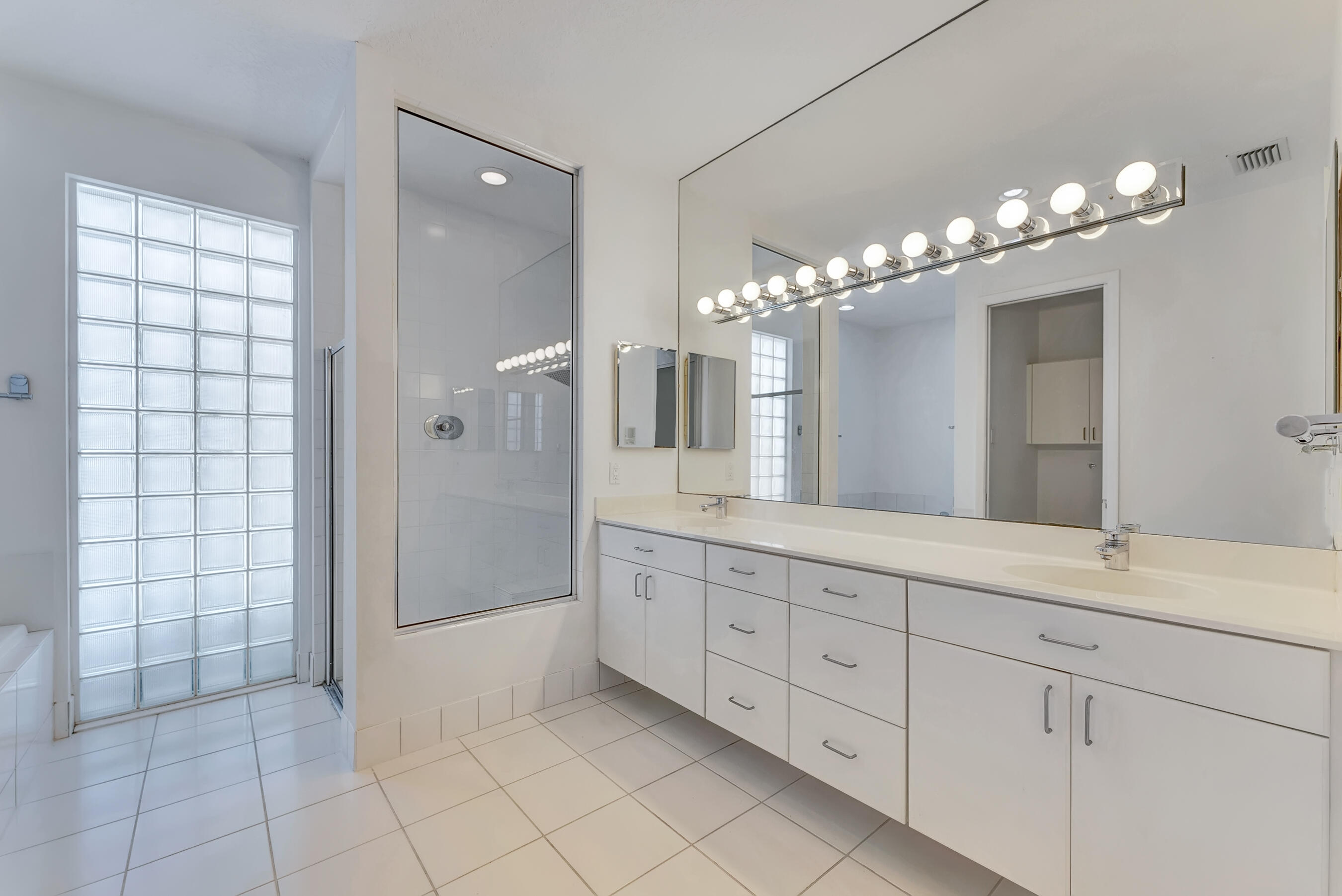 114 Olympus Circle Jupiter, FL 33477 - Photo 36 of 88 a spacious bathroom with a double vanity sink a large mirror and a shower