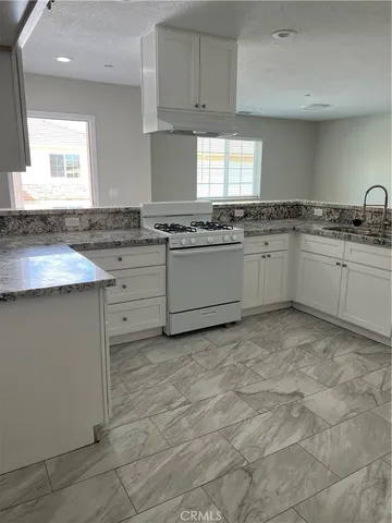 a kitchen with granite countertop a sink stove and cabinets