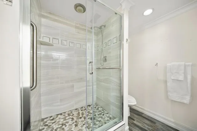a view of a hallway with wooden floor and a bathroom