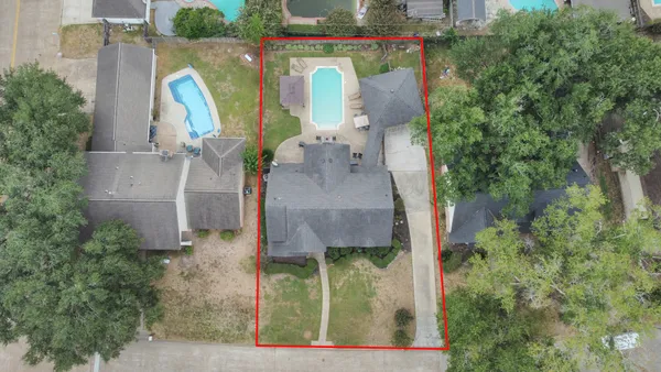 an aerial view of a house with swimming pool and large trees