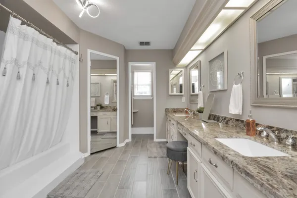 a spacious bathroom with a granite countertop double vanity sink a mirror and a shower