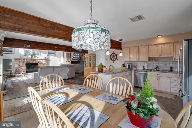 a kitchen with stainless steel appliances granite countertop a refrigerator a sink dishwasher a dining table and chairs with wooden floor