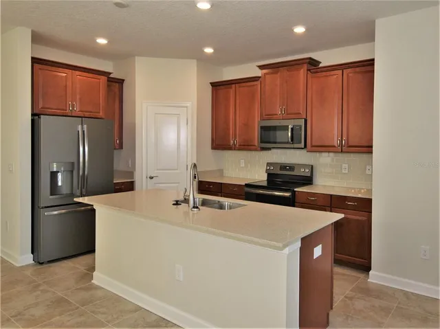 a kitchen with stainless steel appliances granite countertop a refrigerator a sink a stove a microwave and island