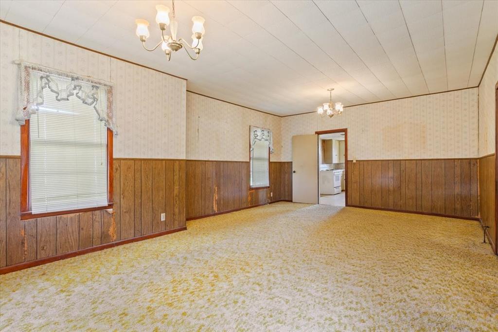 100 County Road 120 C Riesel, TX 76682 - Photo 8 of 25 Spare room with a chandelier, a wainscoted wall, wallpapered walls, wooden walls, and light colored carpet