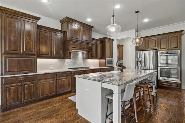 a kitchen with stainless steel appliances granite countertop a sink refrigerator and cabinets