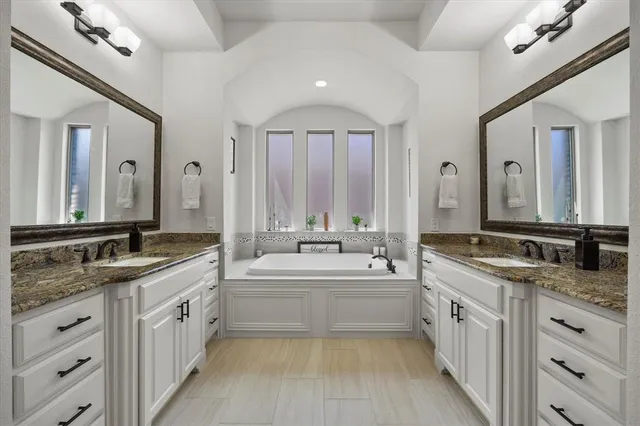 a large bathroom with a double vanity sink a mirror and a bathtub