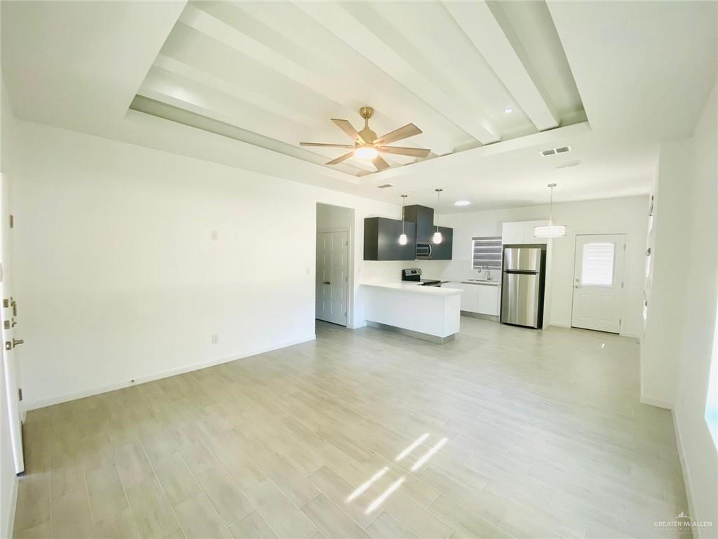 2202 South Sports Drive, Unit 1 Pharr, TX 78577 - Photo 5 of 12 Unfurnished living room with light wood-style floors, a ceiling fan, and beamed ceiling
