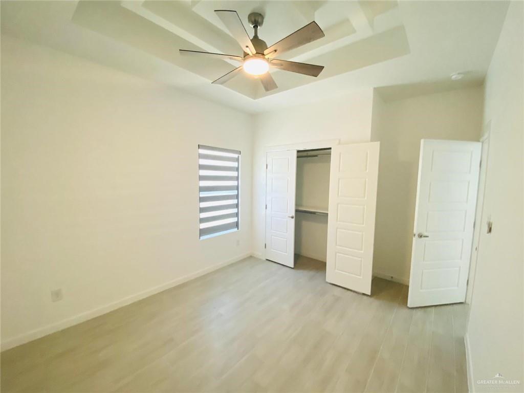 2202 South Sports Drive, Unit 1 Pharr, TX 78577 - Photo 6 of 12 Unfurnished bedroom featuring a tray ceiling, light wood-style flooring, a closet, and a ceiling fan