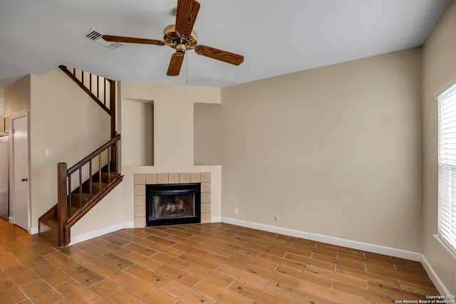 a view of an empty room with wooden floor and a fireplace