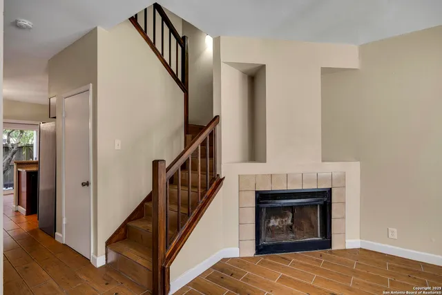 a view of an empty room with wooden floor and a fireplace