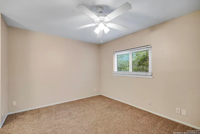 an empty room with a window and a fan