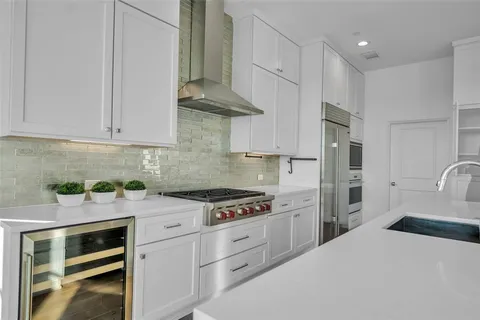 a large kitchen with stainless steel appliances a large counter top a sink a refrigerator and a window