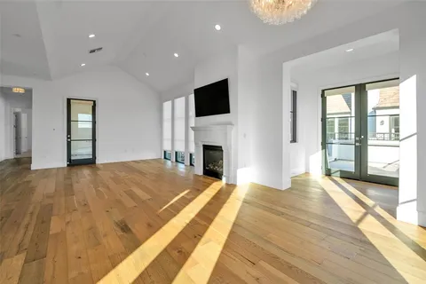 a large white kitchen with kitchen island a large island wooden floor and stainless steel appliances