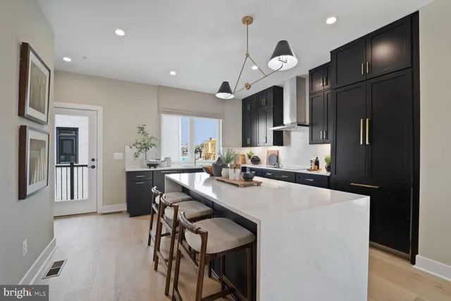 a kitchen with stainless steel appliances kitchen island granite countertop a refrigerator a sink dishwasher a stove and a dining table with wooden floor