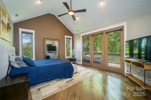 a living room with a bed furniture large windows and wooden floor