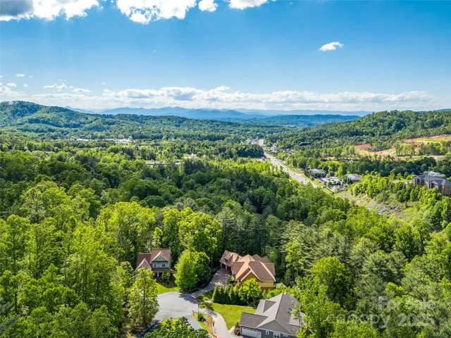 an aerial view of residential house with outdoor space and trees all around