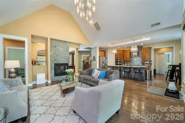 a living room with a bed furniture large windows and wooden floor