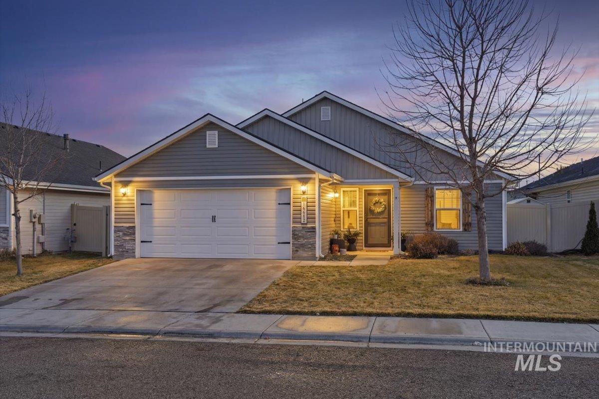 View of front of property with board and batten siding, driveway, an attached garage, and stone siding