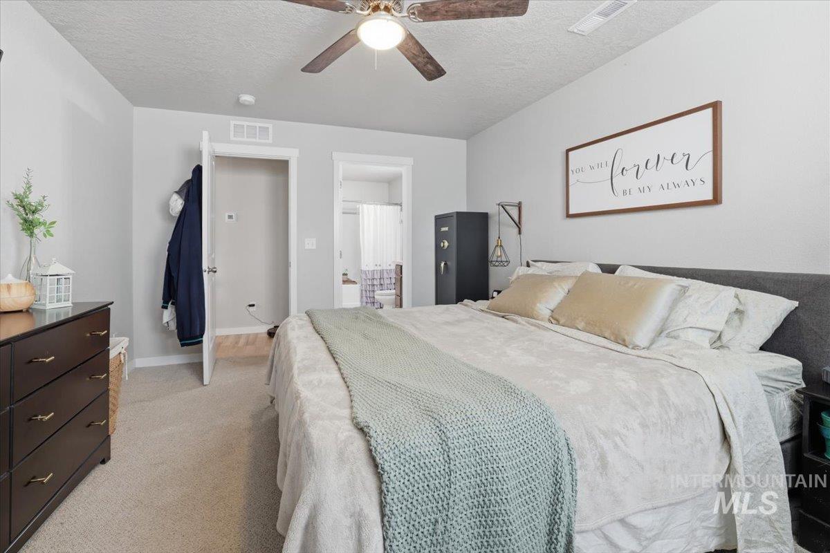 16682 Loggia Avenue Caldwell, ID 83607 - Photo 24 of 46 Bedroom featuring light colored carpet, a textured ceiling, ensuite bathroom, and ceiling fan