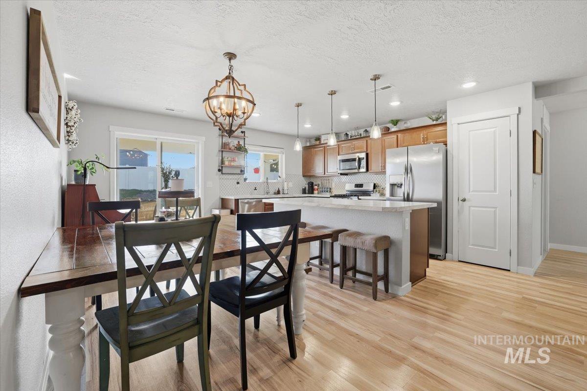16682 Loggia Avenue Caldwell, ID 83607 - Photo 29 of 46 Dining space with light wood-type flooring, a chandelier, and a textured ceiling