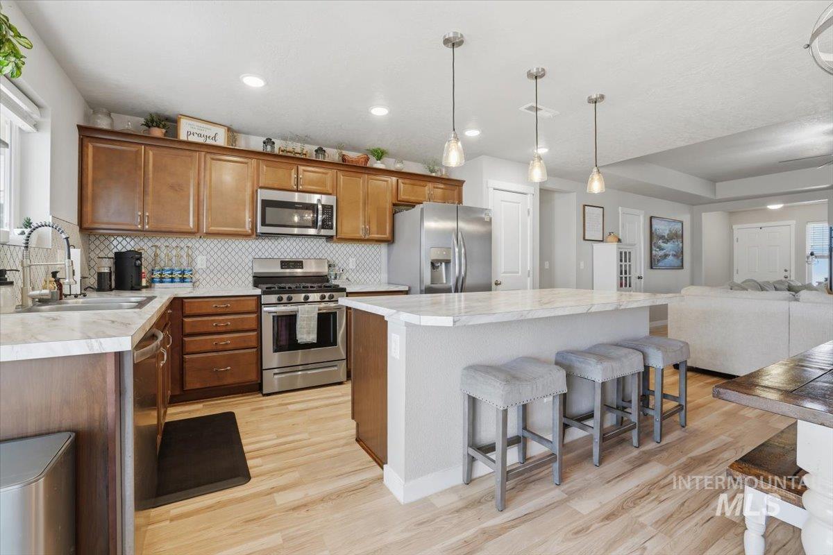 16682 Loggia Avenue Caldwell, ID 83607 - Photo 46 of 46 Kitchen featuring wood finish cabinets, open floor plan, light countertops, stainless steel appliances, and a kitchen bar