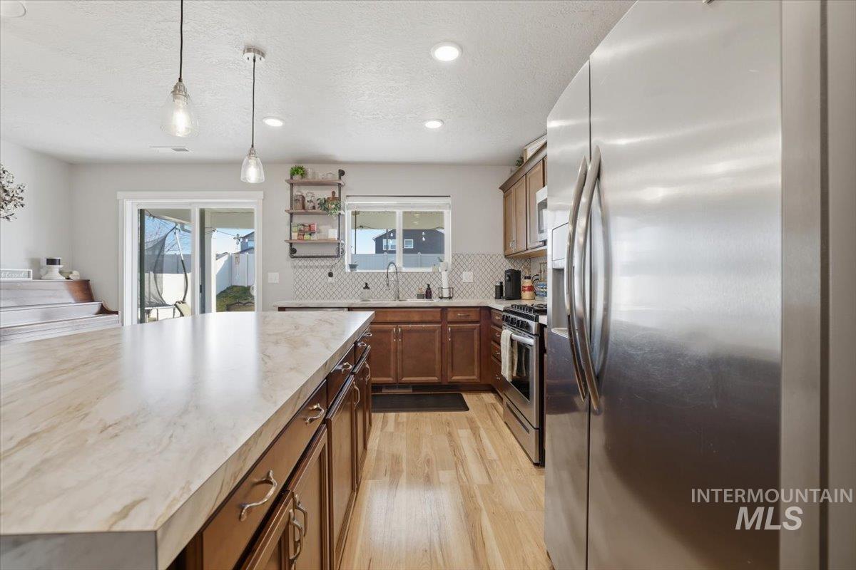 16682 Loggia Avenue Caldwell, ID 83607 - Photo 34 of 46 Kitchen with stainless steel appliances, hanging light fixtures, open shelves, light wood finished floors, and wood finish cabinetry