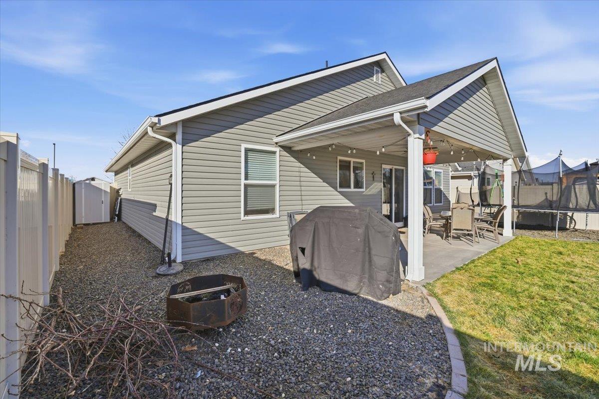 16682 Loggia Avenue Caldwell, ID 83607 - Photo 43 of 46 Rear view of property with a patio, a fenced backyard, a trampoline, and a storage unit