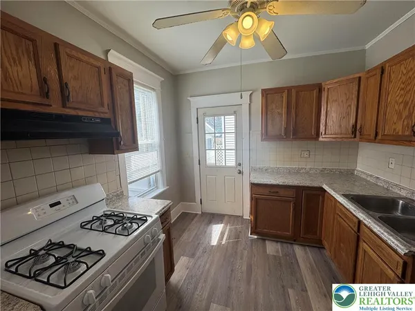 a kitchen with granite countertop a stove a sink dishwasher and a microwave oven with wooden cabinets