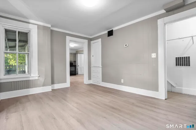 a view of an empty room with wooden floor and a window