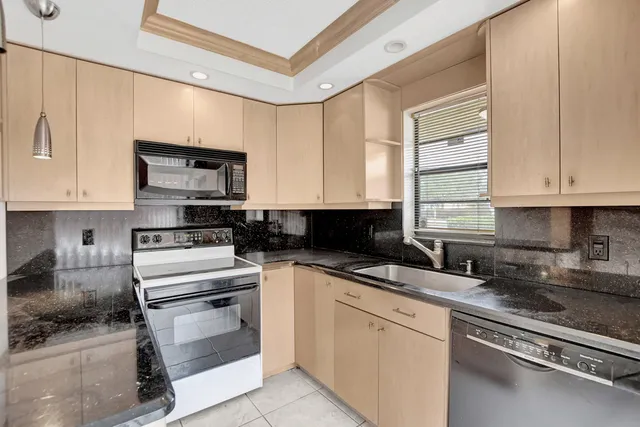 a kitchen with stainless steel appliances granite countertop a stove a sink and white cabinets