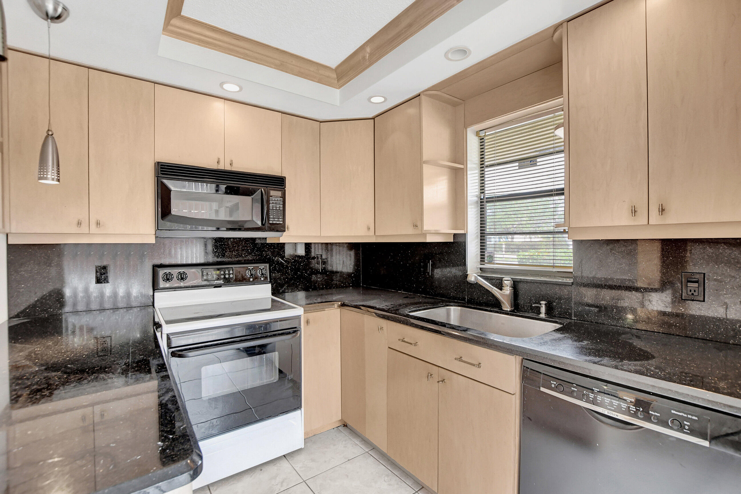 2555 Albatross Road North, Unit 2A Delray Beach, FL 33444 - Photo 12 of 27 a kitchen with stainless steel appliances granite countertop a stove a sink and white cabinets