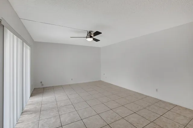 an empty room with white walls and ceiling fan