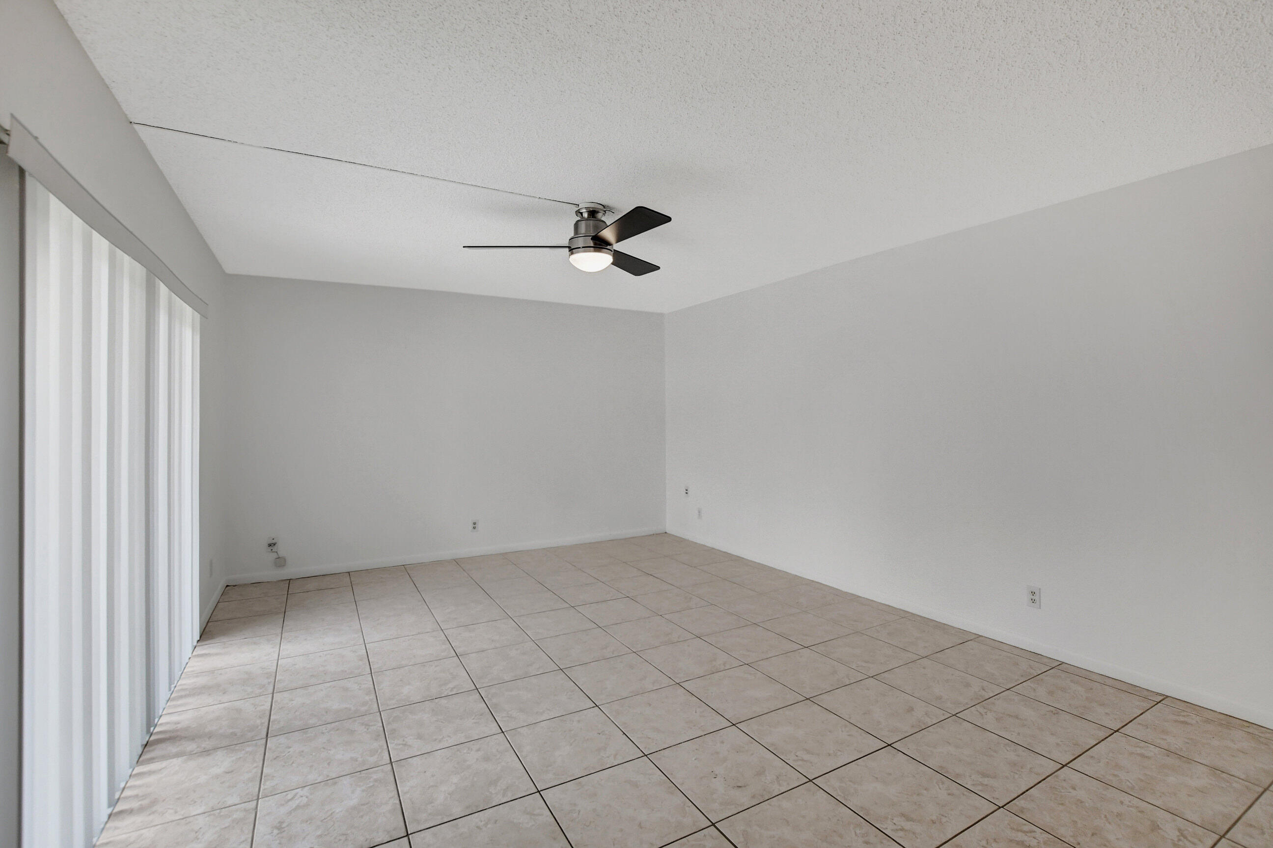 2555 Albatross Road North, Unit 2A Delray Beach, FL 33444 - Photo 5 of 27 an empty room with white walls and ceiling fan