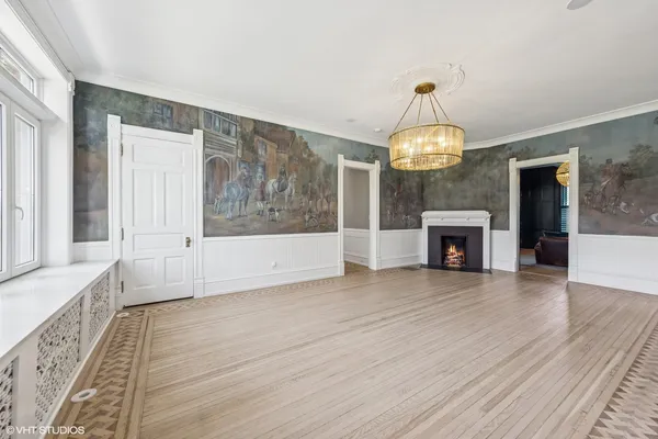 a view of an empty room with wooden floor fireplace and a window