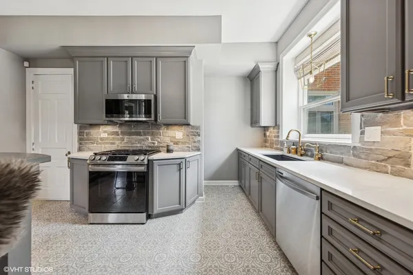 a dining hall with stainless steel appliances kitchen island granite countertop a table chairs and a large window