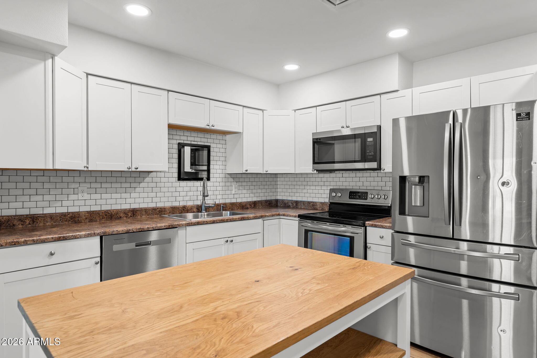 a kitchen with granite countertop a refrigerator stove a sink and dishwasher with wooden floor