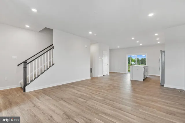 a view of a hallway with wooden floor and a kitchen space
