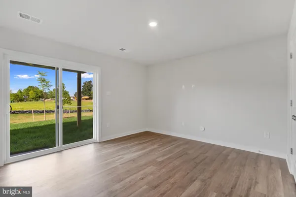 a view of empty room with wooden floor and floor to ceiling window