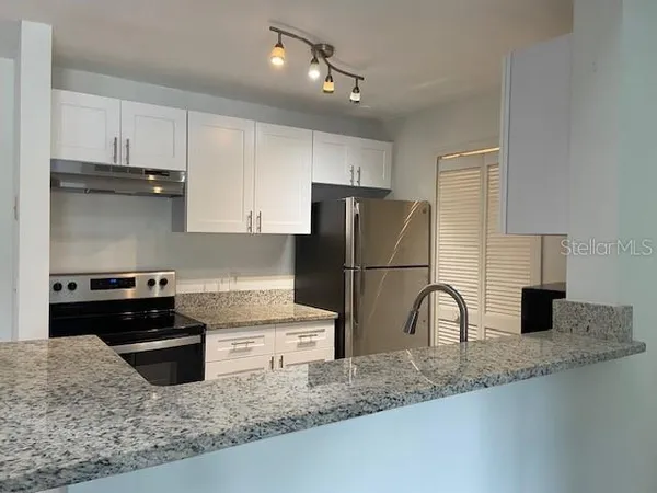 a kitchen with a stove top oven and refrigerator