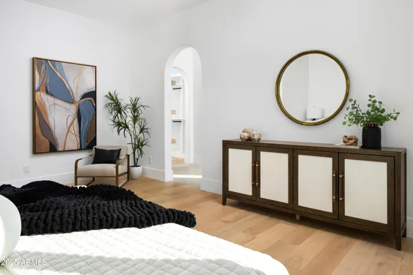 a bedroom with a bed mirror and painting on the wall