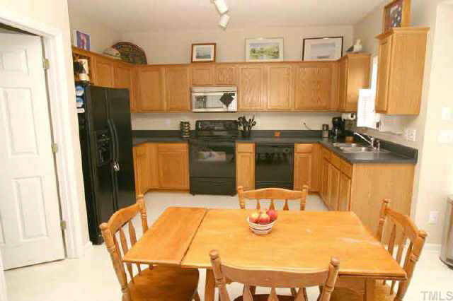 6507 Draebury Lane Durham, NC 27713 - Photo 4 of 9 a kitchen with stainless steel appliances kitchen island granite countertop a refrigerator a stove a sink dishwasher with a dining table and chairs