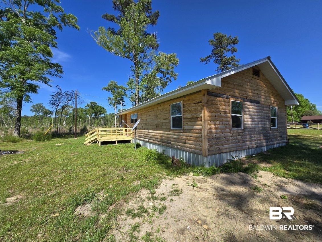 6464 Ridge Road Brewton, AL 36426 - Photo 5 of 14 View of property exterior featuring a lawn, a deck, and log veneer siding