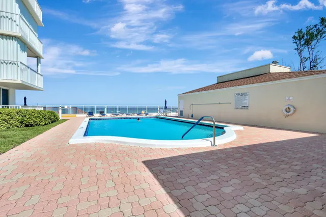 a front view of multi story residential apartment building with yard and sign board